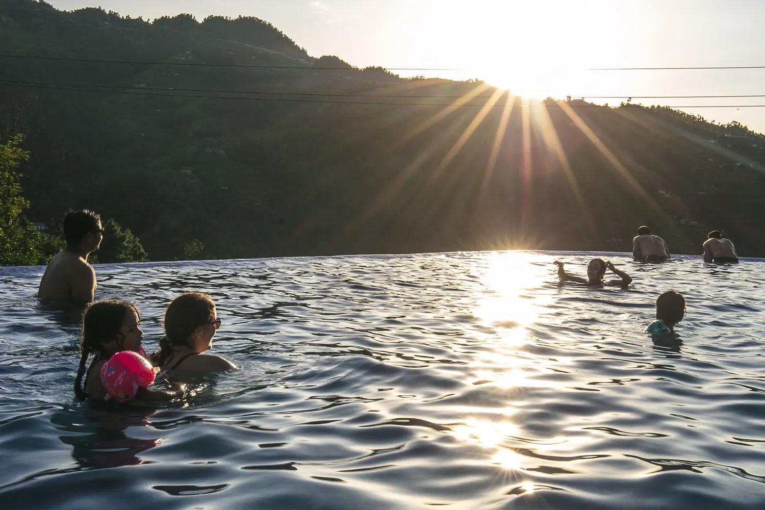Enjoying a relaxing evening by the swimming pool at a resort in Kulekhani, surrounded by green hills.