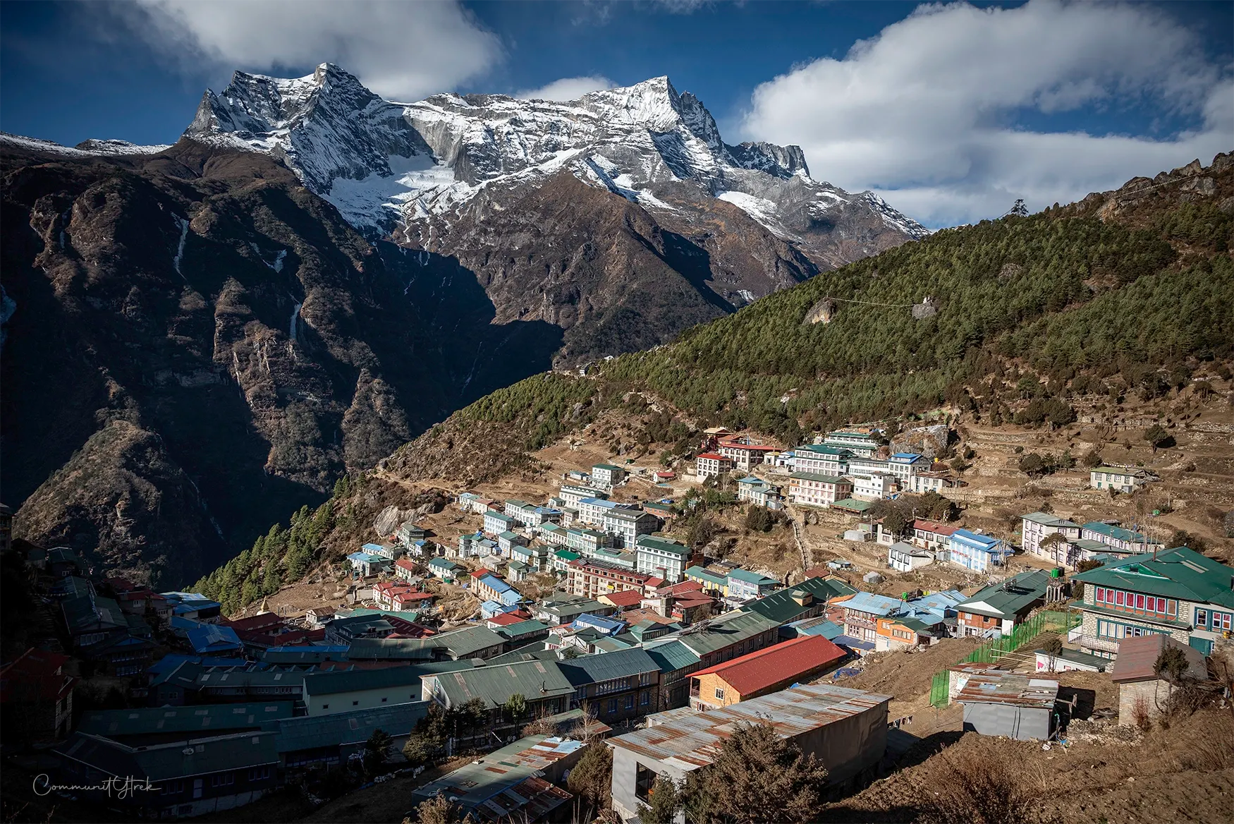 Winter view of Namche Bazaar surrounded by snow-capped Himalayan mountains under a clear blue sky.