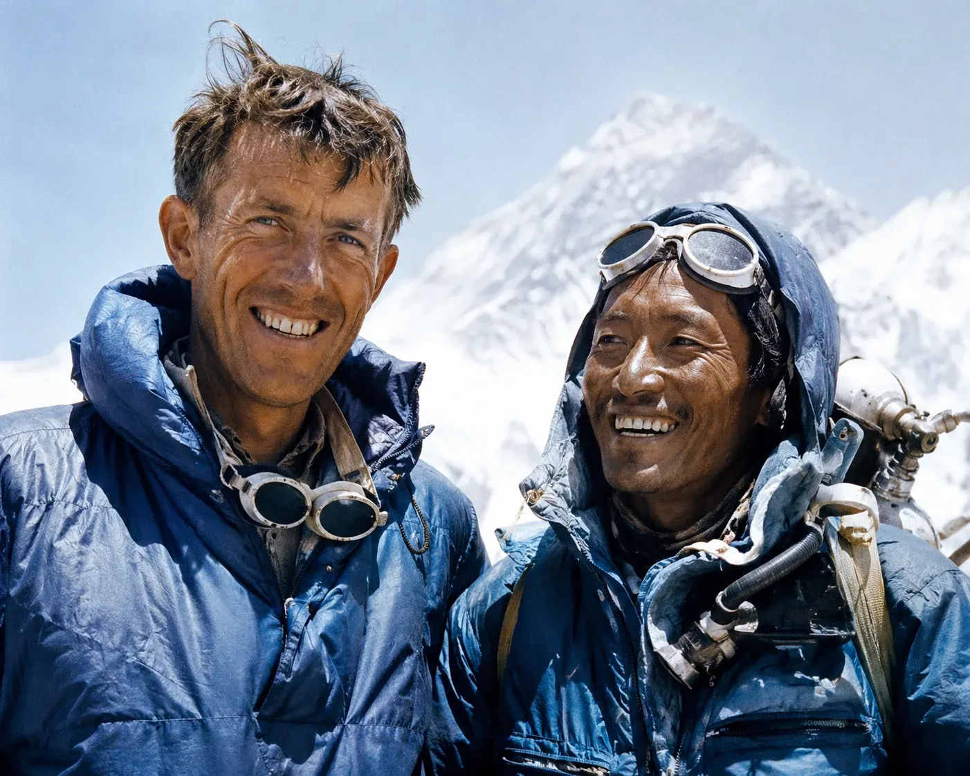 Sir Edmund Hillary and Tenzing Norgay Sherpa wearing mountaineering gear with the snowy Himalayas in the background.